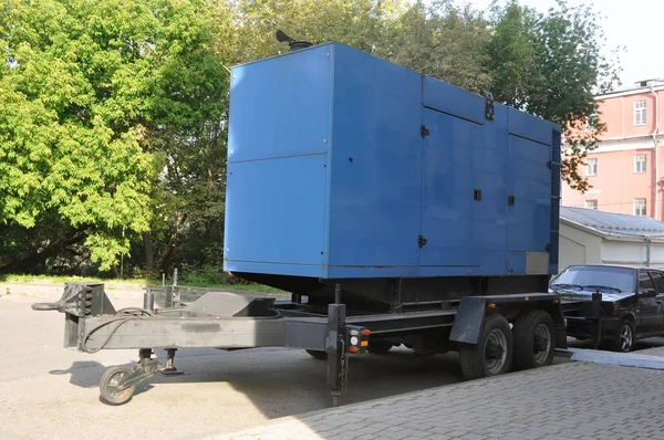 Blue standby mobile diesel generator for office building connected by cable wire to office building