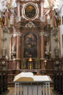 İncil ya da dua kitabı Katolik kilisesindeki dua bankında seçici bir odak noktası olarak yatıyor. Dikey