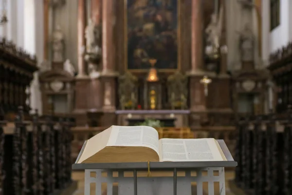 Bible or prayer book lying on praying bench in catholic church, selective focus. Horizontal