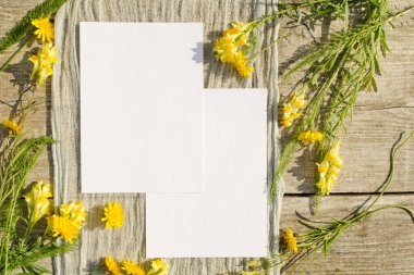 Kırsal ve doğal olarak eski ahşap bir arka planda sarı çiçekli yaz kırtasiye tasarımı sahnesi. Tebrik kartı ya da düğün davetiyesi için maket kartı. Düz yatıyordu, üst
