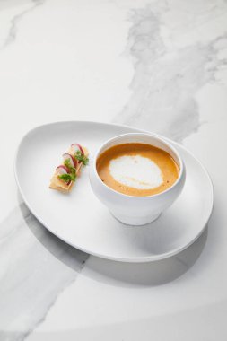 Kabuklu ekmekle servis edilen Kral karides çorbası, beyaz mermer arka planda kremalı karides çorbası.