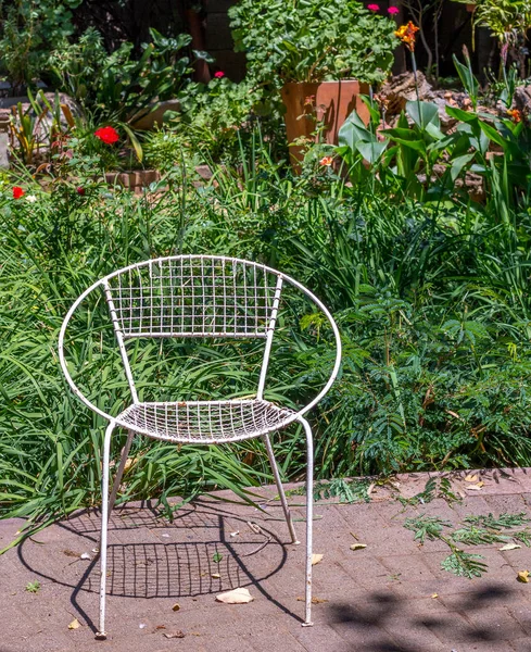 Weathered white metal garden chair isolated in a green garden image with copy space in portrait format