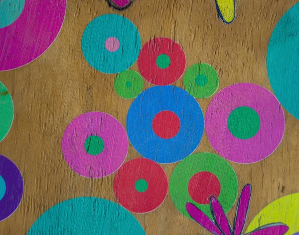 Colorful circles and flowers hand painted onto a wooden surface image for background use with copy space