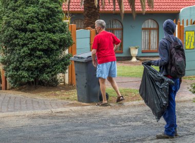 Johannesburg, Güney Afrika - 2 Nisan 2019: tanımlanamayan evsiz adam kaldırımda içinden kullanım veya gıda öğeleri aramak için bir çöp kutusu yerleştirmek bir Tanımlanamayan ev sahibi bekler