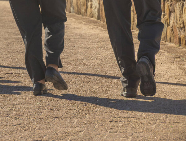 The isolated lower legs of a couple walking on a promenade image in landscape format with copy space