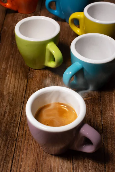 各种颜色的咖啡杯和一杯热气腾腾的浓缩咖啡 — 图库照片
