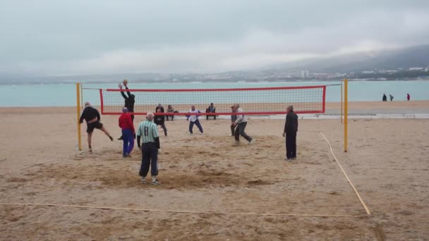 Las personas mayores juegan voleibol en la playa . — Vídeos de Stock