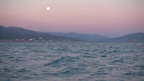 Hermosa puesta de sol, luna naciente sobre el mar y la montaña . — Vídeos de Stock