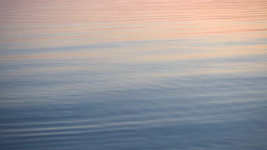 Görkemli günbatımı sakin su yüzeyinden yansıyan.