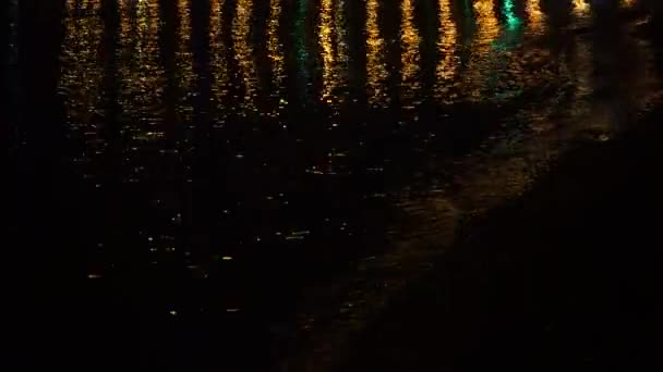 五彩缤纷的城市灯光映在水面和夜晚的沙滩上. — 图库视频影像