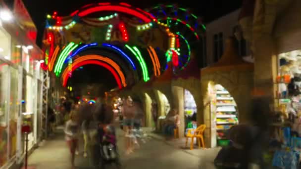 Ingang in attractiepark bij nacht, mensen lopen en baai souvenirs. — Stockvideo