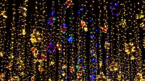 Όμορφες πολύχρωμες διακοσμήσεις διακοπών, Χριστουγεννιάτικα παιχνίδια, γιρλάντες ταλαντεύονται στον αέρα στο νυχτερινό ουρανό. — Αρχείο Βίντεο