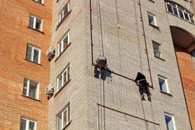 Industrial climbing. Workers hang the advertising on a building. Work at height clipart