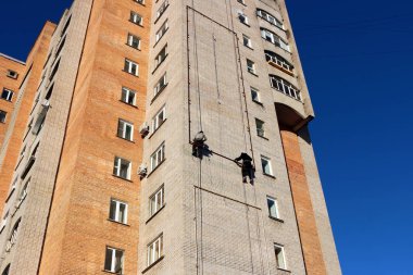 Endüstriyel tırmanma. İşçiler bir bina üzerinde reklam asmak. Yükseklikte çalışma