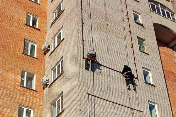 Industrial climbing. Workers hang the advertising on a building. Work at height