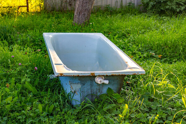 Чугунная ванна посреди газона в саду
