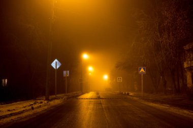 Yolun gece sırasında kalın bir sis loş fenerler tarafından aydınlatılmış