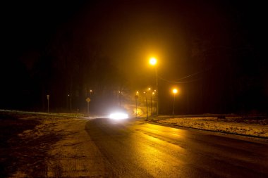 Yolun gece sırasında kalın bir sis loş fenerler tarafından aydınlatılmış