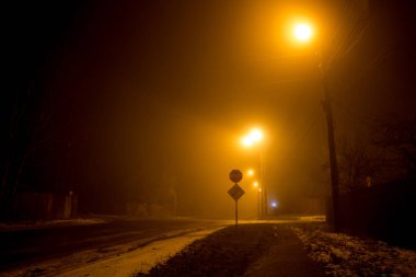 Yolun gece sırasında kalın bir sis loş fenerler tarafından aydınlatılmış