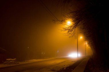 Yolun gece sırasında kalın bir sis loş fenerler tarafından aydınlatılmış