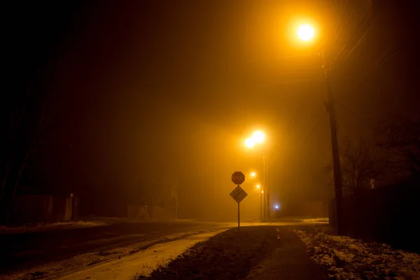 濃い霧の中に薄暗いランタンに照らされた夜の道 — ストック写真