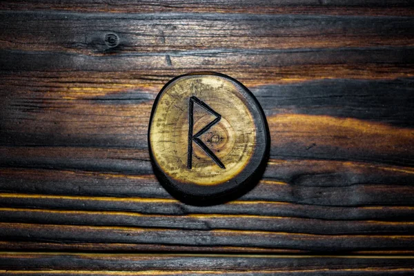 Rune Raido carved from wood on a wooden background - Elder Futhark