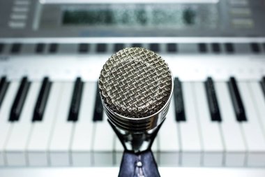 Raf yakın çekim üzerinde gümüş mikrofon. Klavye synthesizer içinde belgili tanımlık geçmiş