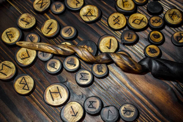 Homemade magic wands and wooden runes on a dark wooden background