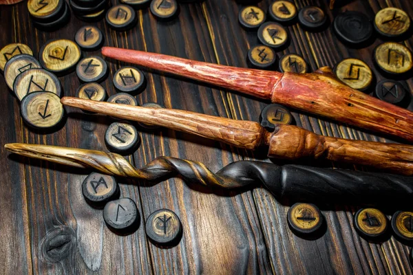 Homemade magic wands and wooden runes on a dark wooden background