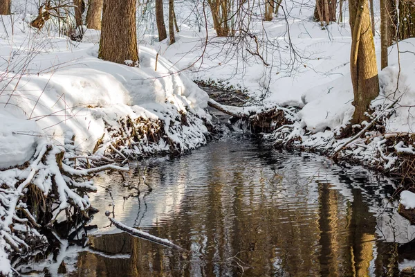 View of a small river in the forest running in the winter among white snow