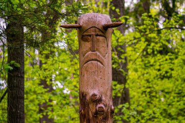 Image of the Slavic deity Veles carved from a tree trunk on a neo-Pagan temple in the forest. Kaluzhskiy region, Russia. Veles - the god of cattle breeding, wealth and wisdom clipart