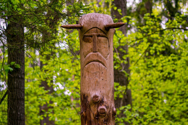 Image of the Slavic deity Veles carved from a tree trunk on a neo-Pagan temple in the forest. Kaluzhskiy region, Russia. Veles - the god of cattle breeding, wealth and wisdom