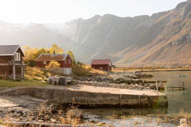 Aşağı üzerinden bir kulübe Tromso, Norveç kıyı üzerinde doğal bir kırsal manzara sisli bir günde parlayan bir dağ tepe üzerinde lens ile ışık demeti flare