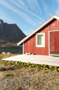 Ahşap Norveç plaj kulübe taşlarla kırpılmış bakış Tromso fiyort, Arctic Circle, Norveç ve dağ tepe bir güneşli mavi gökyüzü gün bakan kıyı üzerinde kapatın