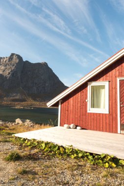 Ahşap Norveç plaj kulübe taşlarla kırpılmış bakış Tromso fiyort, Arctic Circle, Norveç ve dağ tepe bir güneşli mavi gökyüzü gün bakan kıyı üzerinde kapatın