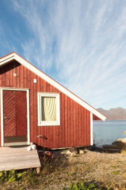 Ahşap Norveç plaj kulübe taşlarla kırpılmış bakış Tromso fiyort, Arctic Circle, Norveç ve dağ tepe bir güneşli mavi gökyüzü gün bakan kıyı üzerinde kapatın