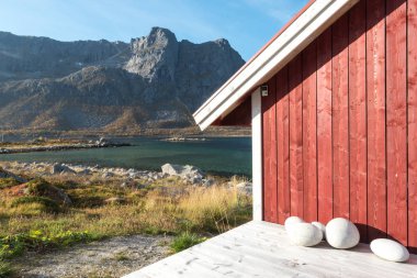 Ahşap Norveç plaj kulübe taşlarla kırpılmış bakış Tromso fiyort, Arctic Circle, Norveç ve dağ tepe bir güneşli mavi gökyüzü gün bakan kıyı üzerinde kapatın