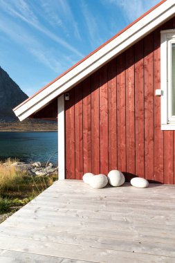 Ahşap Norveç plaj kulübe taşlarla kırpılmış bakış Tromso fiyort, Arctic Circle, Norveç ve dağ tepe bir güneşli mavi gökyüzü gün bakan kıyı üzerinde kapatın