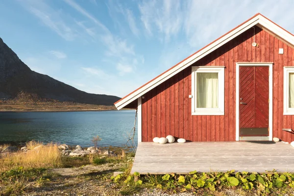 Ahşap Norveç plaj kulübe taşlarla görünümünü Tromso fiyort, Arctic Circle, Norveç ve dağ tepe bir güneşli mavi gökyüzü gün bakan kıyı üzerinde
