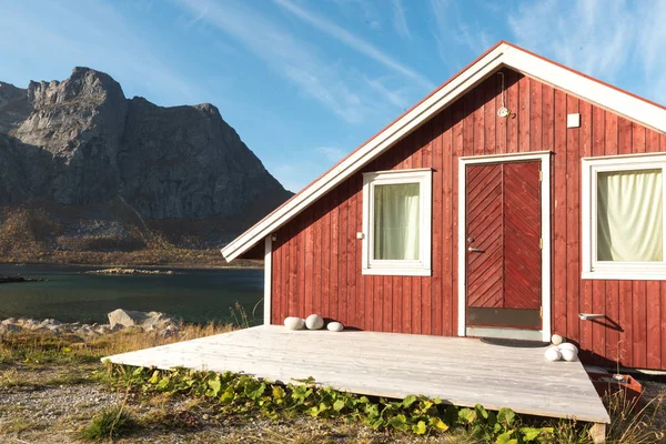 Ahşap Norveç plaj kulübe taşlarla görünümünü Tromso fiyort, Arctic Circle, Norveç ve dağ tepe bir güneşli mavi gökyüzü gün bakan kıyı üzerinde