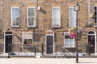 Ön cepheler ve tarihsel tuğla uzun boylu windows ve demir kapının önünde bir bisiklet kaldırım ve elektrik direği ile korkuluk ile Londra Teras Evler, kemerli kapılar