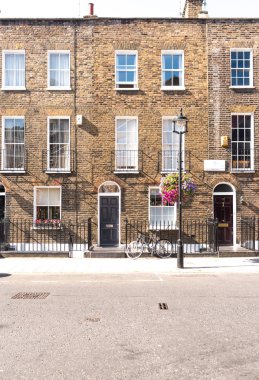 Ön cepheler ve tarihsel tuğla uzun boylu windows ve demir kapının önünde bir bisiklet kaldırım ve elektrik direği ile korkuluk ile Londra Teras Evler, kemerli kapılar