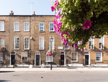Ön cepheler ve tarihsel tuğla uzun boylu windows ve demir kapının önünde bir bisiklet kaldırım ve elektrik direği ile korkuluk ile Londra Teras Evler, kemerli kapılar