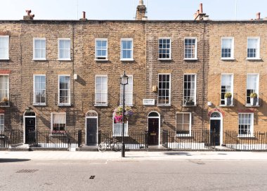 Ön cepheler ve tarihsel tuğla uzun boylu windows ve demir kapının önünde bir bisiklet kaldırım ve elektrik direği ile korkuluk ile Londra Teras Evler, kemerli kapılar