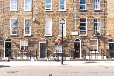 Ön cepheler ve tarihsel tuğla uzun boylu windows ve demir kapının önünde bir bisiklet kaldırım ve elektrik direği ile korkuluk ile Londra Teras Evler, kemerli kapılar