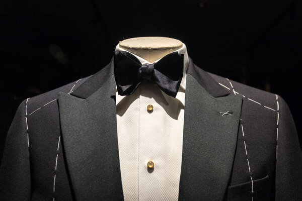 Close up on top part of tailored jacket on mannikin with black bow tie and sequined buttons on shirt
