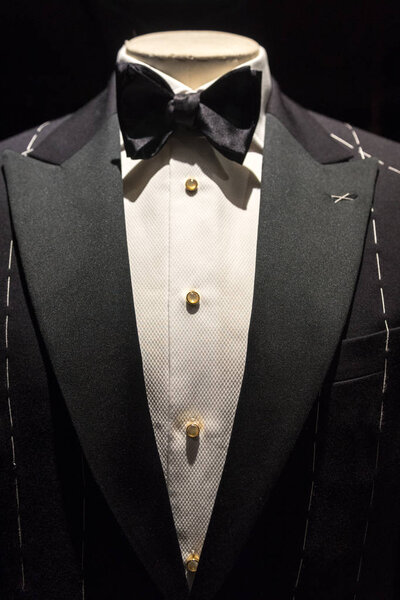 Close up on top part of tailored jacket on mannikin with black bow tie and sequined buttons on shirt