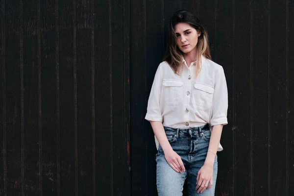 Une jeune hipster belle femme aux longs cheveux bruns en été avec un jean denim au fond marron — Photo