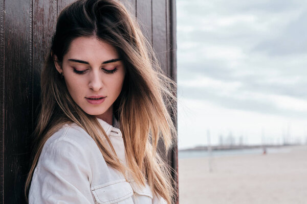 A young hipster beautiful woman with long brown hair in summer with denim jeans with a brown background