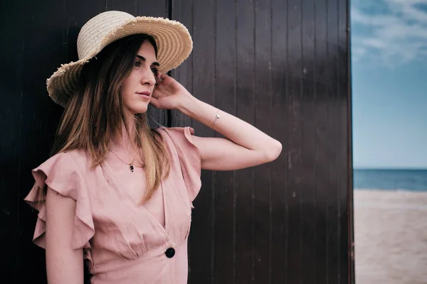 Une jeune femme debout sur un fond de bois brun avec un chapeau dans une journée d'été — Photo